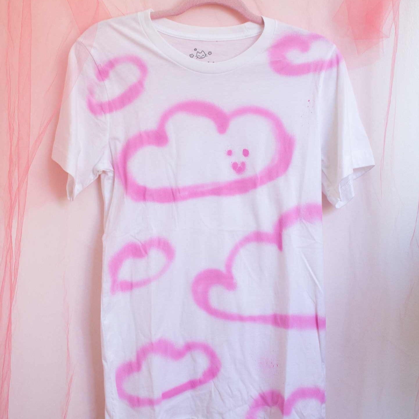 Photo du t-shirt blanc avec nuages roses peinturés à l'aérosol