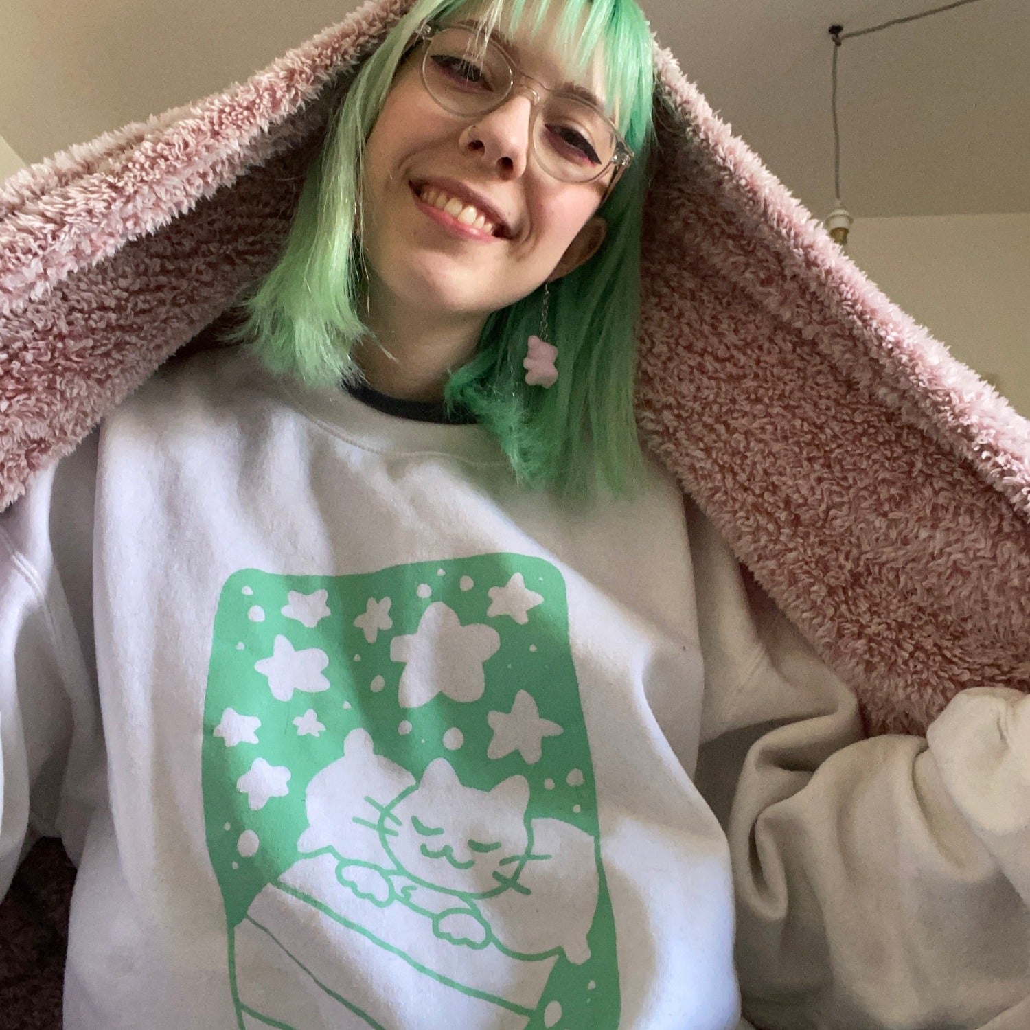Selfie d'Audrey qui porte le coton ouaté blanc Ronron Nightclub à imprimé d'un chat qui dors turquoise